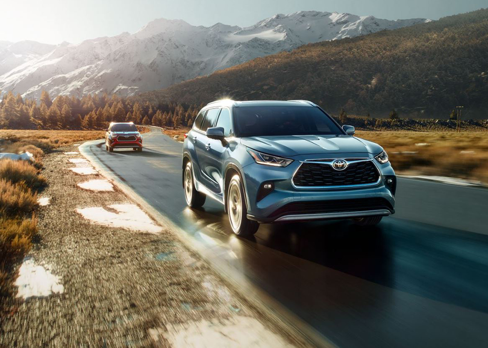 A Toyota Highlander drives away from mountains.