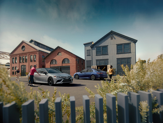 Two toyota sedans, parked outside a couple of shops.