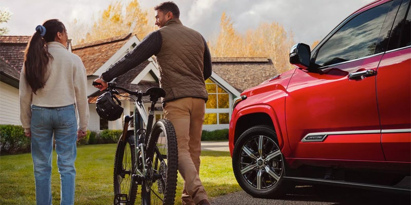 Exterior view of red Sequoia parked with man and woman next to a bike