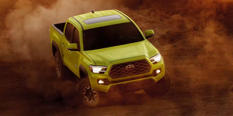 View of yellow Tacoma driving in the desert