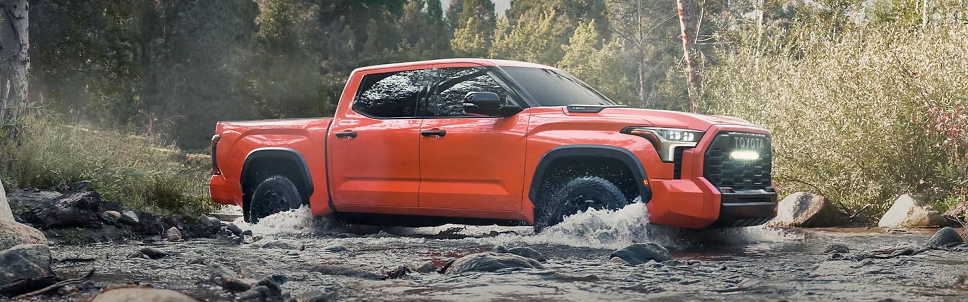 Exterior view of orange Tundra driving through water