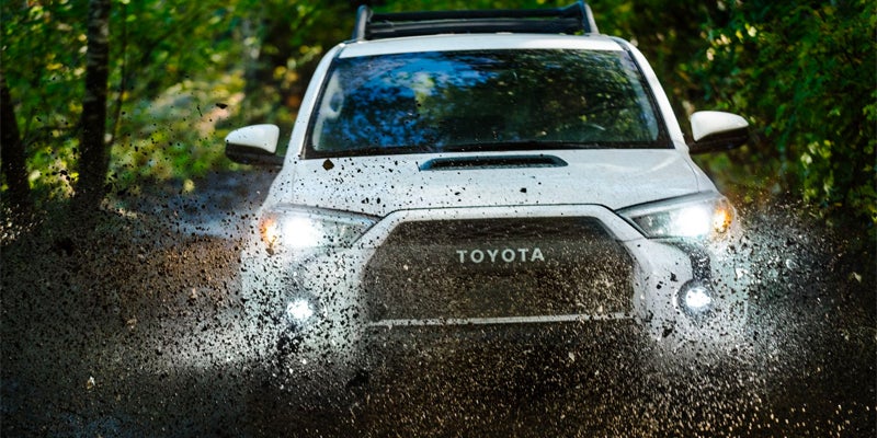 Front view of a white 2024 Toyota 4Runner drives through mud