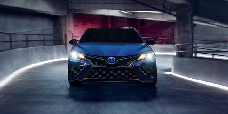 Front view of a navy blue Toyota Camry Hybrid driving up a parking ramp