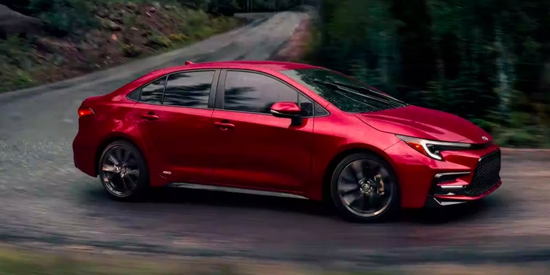 Side view of a red Toyota Corolla driving around a curvy road