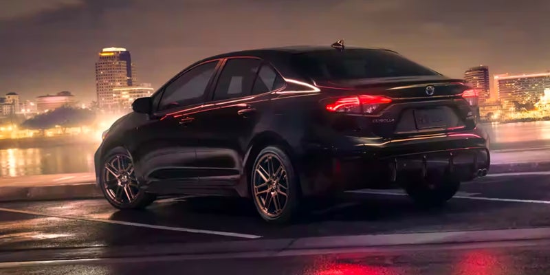 rear view of a Toyota Corolla parked in viewing range of a city at night