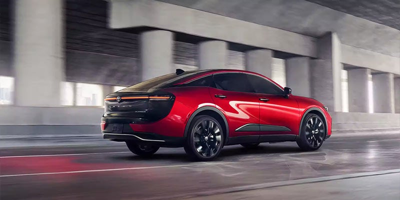 Side view of a red 2024 Toyota Crown driving under a highway overpass