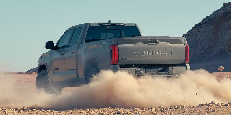 Rear view of a gray Toyota Tundra driving through dirt